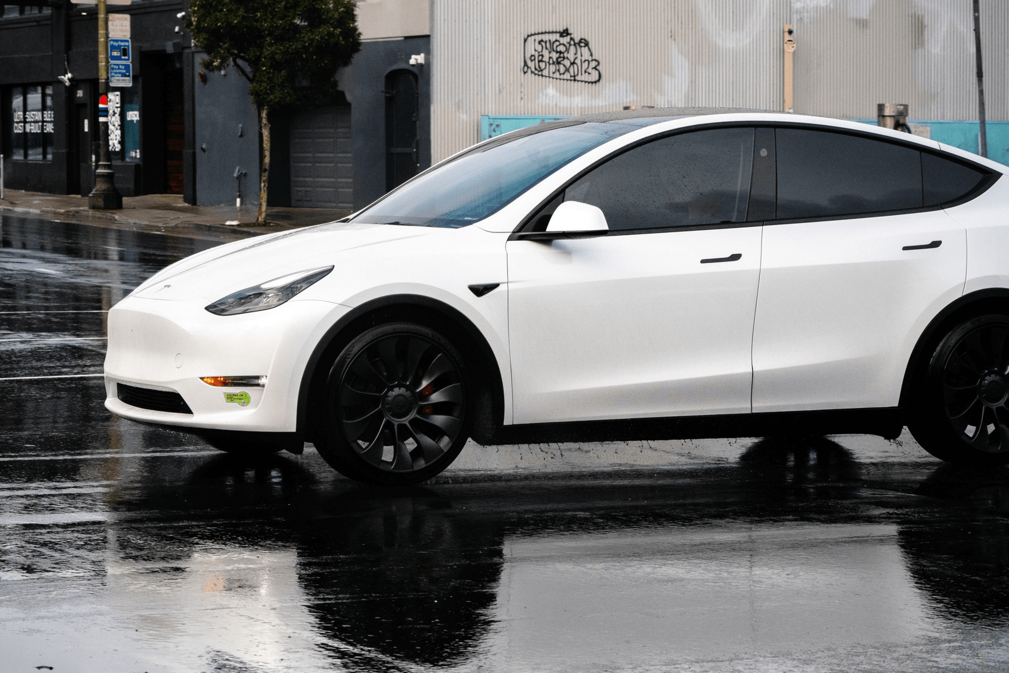 A white Tesla Model Y with no front license plate.