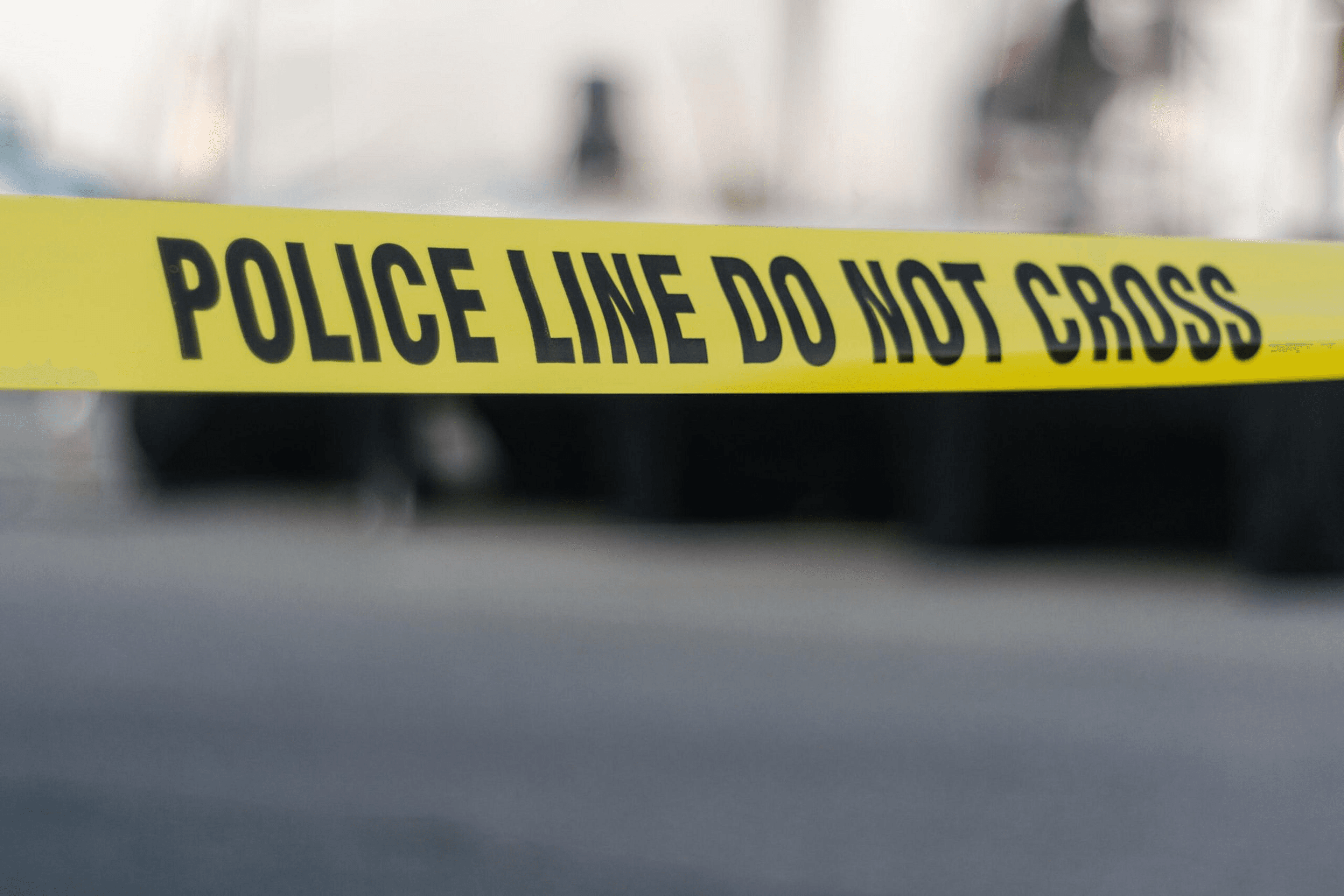Yellow police tape stretches across a distant scene and warns viewers not to cross its path